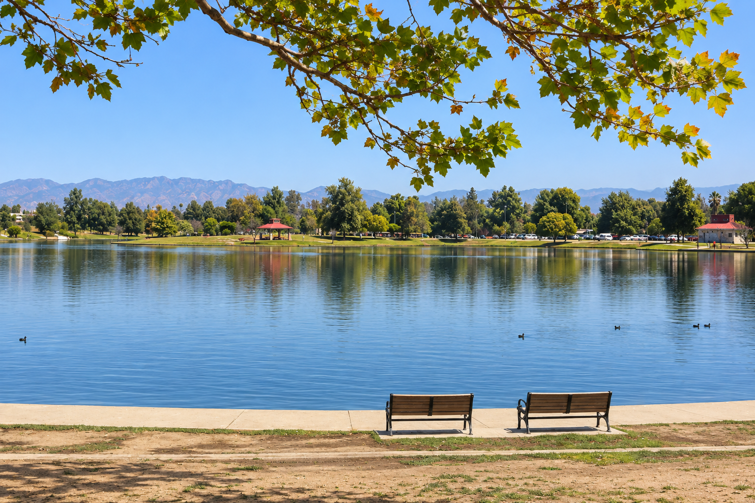 Lake Balboa reflecting trees and mountains with two benches beside the water